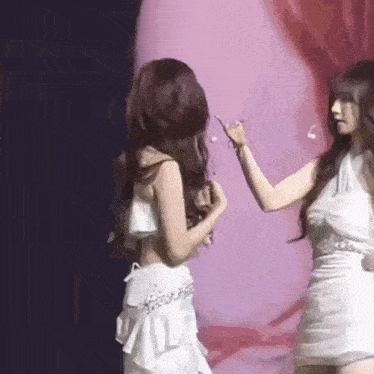 two women are standing next to each other on a stage .
