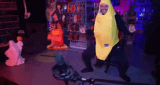 a man in a banana costume is dancing in front of a microphone in a dark room .