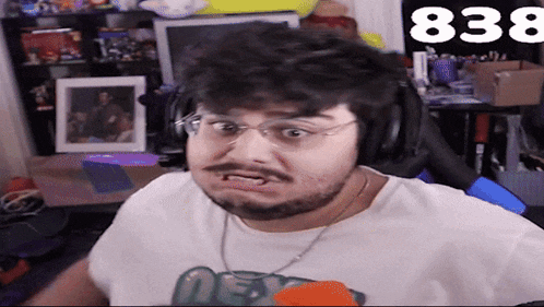 a man with a beard wearing headphones and a white shirt with the number 838 behind him