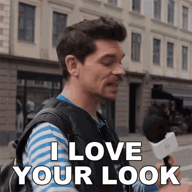 a man with a backpack is holding a microphone and says i love your look