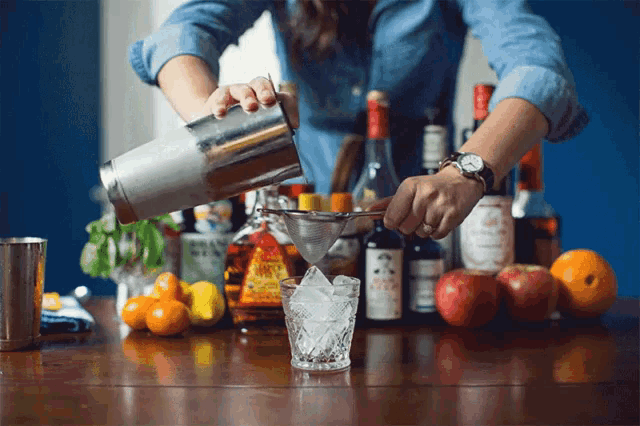 a bartender is pouring a drink into a glass