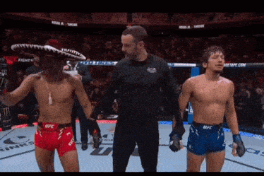 a referee stands between two fighters wearing shorts that say ufc