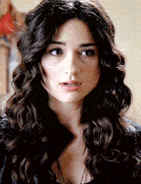 a woman with long curly hair is wearing a black jacket
