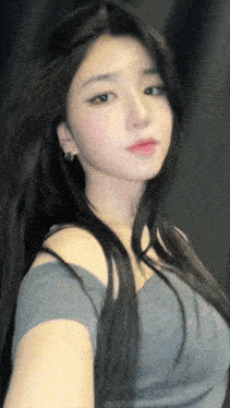 a woman with long black hair is wearing a gray top