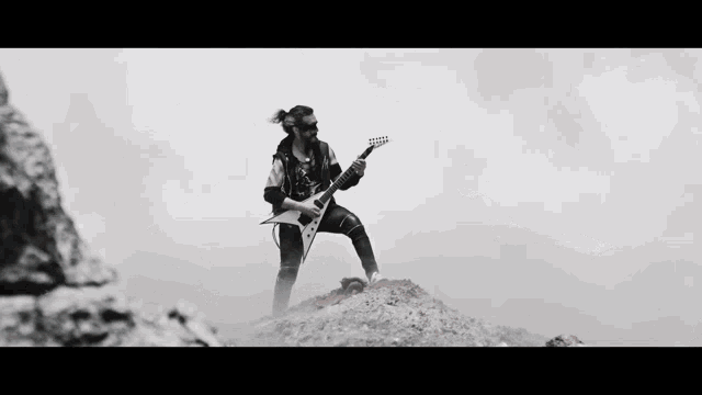 a man playing a guitar on top of a hill