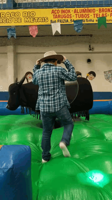 a man is riding a bull in front of a sign that says aço inox