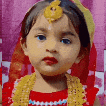 a little girl is wearing a red dress and a gold necklace