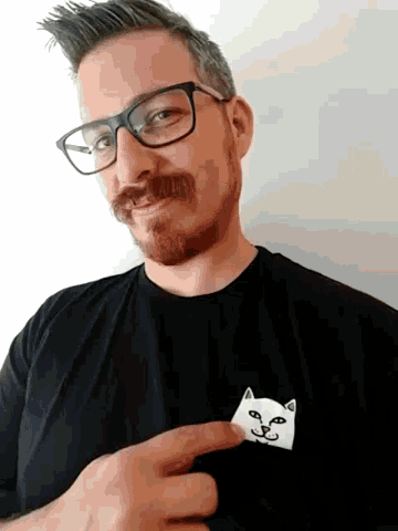 a man wearing glasses and a black shirt has a cat face on his shirt