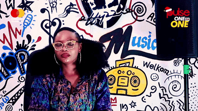 a woman is sitting in front of a wall that says music on it