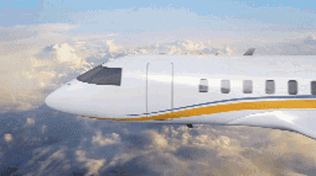 a white and yellow airplane flying through the clouds