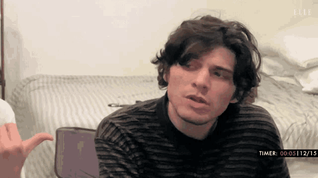 a man is sitting in front of a bed with a timer that says 00 05 12 15
