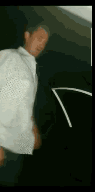 a man in a white shirt and tie is standing in front of a black wall