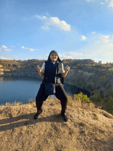 a person giving the middle finger while standing on top of a hill overlooking a lake