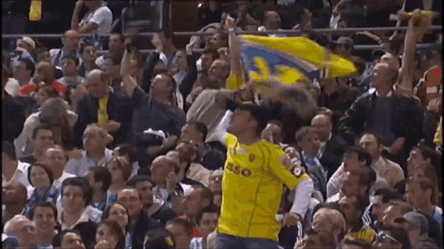 a man in a yellow jersey that says eso is holding a flag in front of a crowd