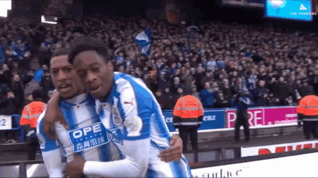 two soccer players are hugging each other and one of their shirts says opel