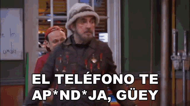 a man in a hat is standing next to another man and says el telefono te ap * nd * ja guey .