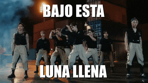 a group of people are dancing in front of a sign that says " bajo esta luna llena "
