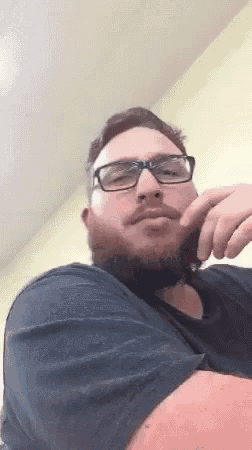 a man with a beard wearing glasses and a black shirt .