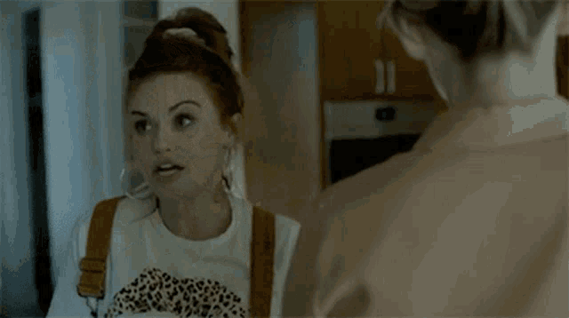 a woman in a leopard print shirt is talking to another woman in a kitchen
