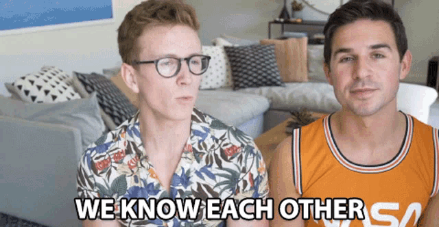 two men are sitting in a living room and one of them is wearing a nasa shirt