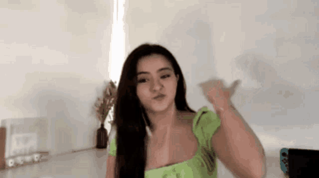 a woman in a green top is making a funny face .