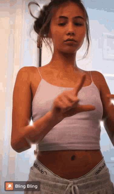 a woman wearing a white tank top and grey shorts is pointing at something