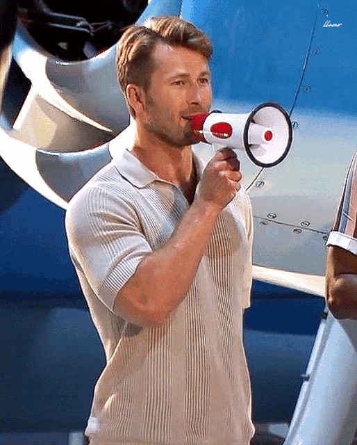 a man in a white shirt is holding a megaphone in front of an airplane