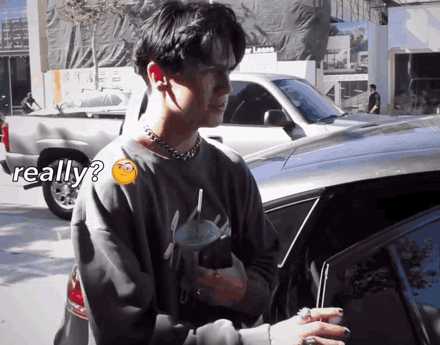 a man standing next to a car with a smiley face on his chest and the word really on the bottom