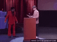 a man in a red suit stands behind a podium with a make gifs at gifsoup.com button