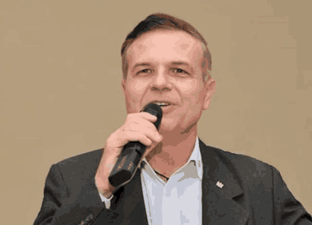 a man in a suit is holding a microphone in his hand