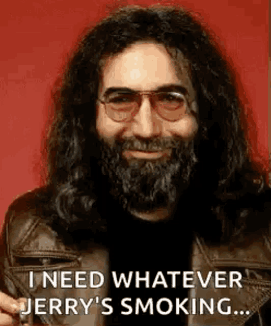 a man with a beard and glasses is smoking a cigarette and smiling .