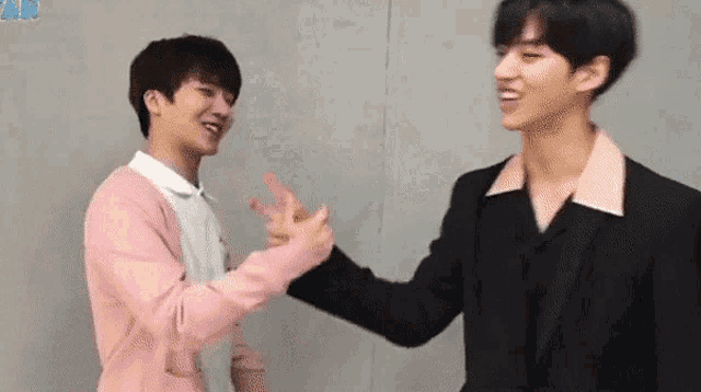 two young men are standing next to each other and giving each other thumbs up .