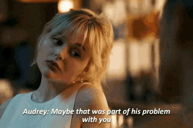 a woman in a white dress is sitting at a table and says " audrey maybe that was part of his problem with you "