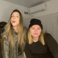 two women are standing next to each other in a room and one is wearing a black beanie .
