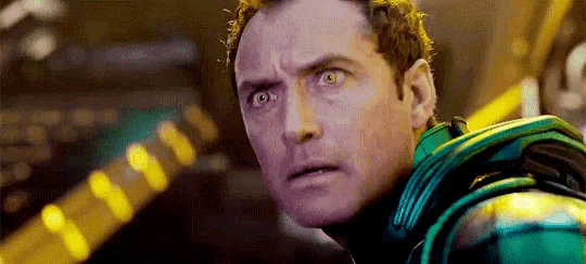 a close up of a man 's face with a surprised look on his face while wearing a green suit .