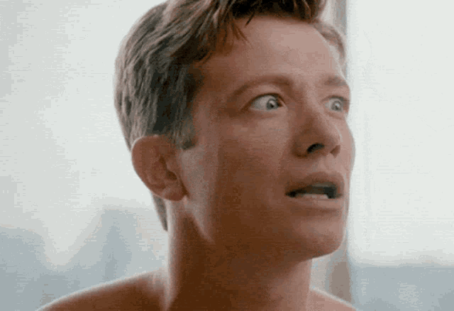 a man without a shirt is looking up with his mouth open