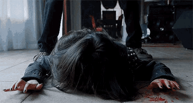 a woman is laying on the floor with blood coming out of her hands .