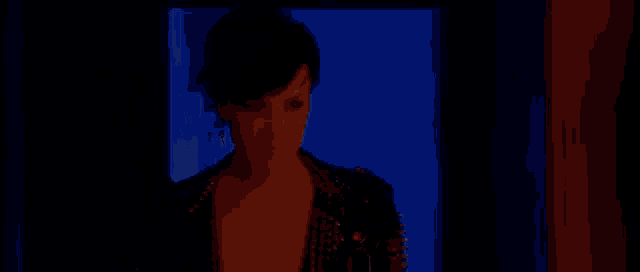 a woman wearing a leather jacket with spikes on it is standing in a doorway .