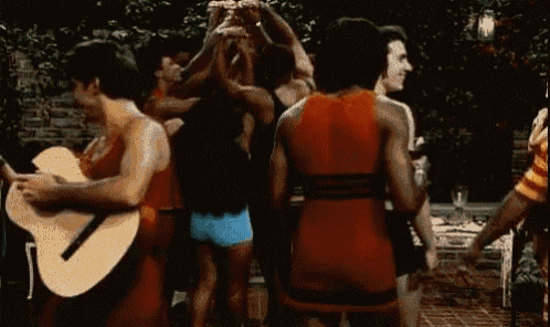a man is playing a guitar while a group of people are dancing in a circle .