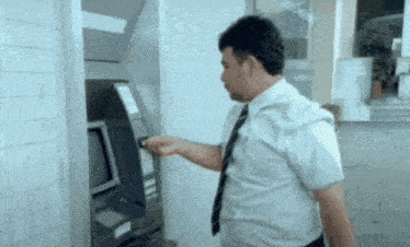 a man in a white shirt and tie is inserting a credit card into an atm machine