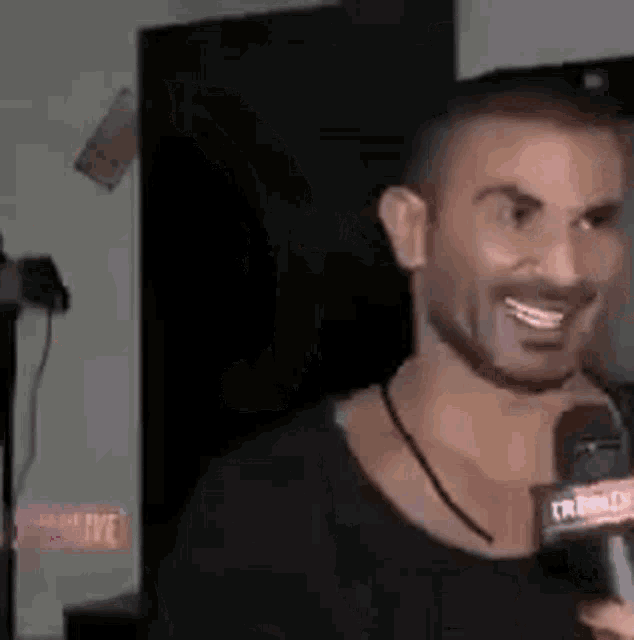 a man with a beard is talking into a microphone .
