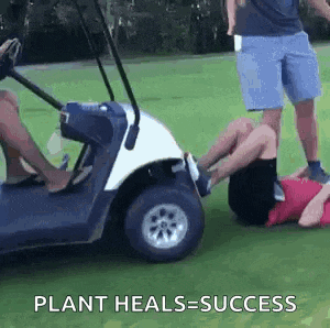 a person is laying on the ground next to a golf cart with the words `` plant heals = success '' written on it .