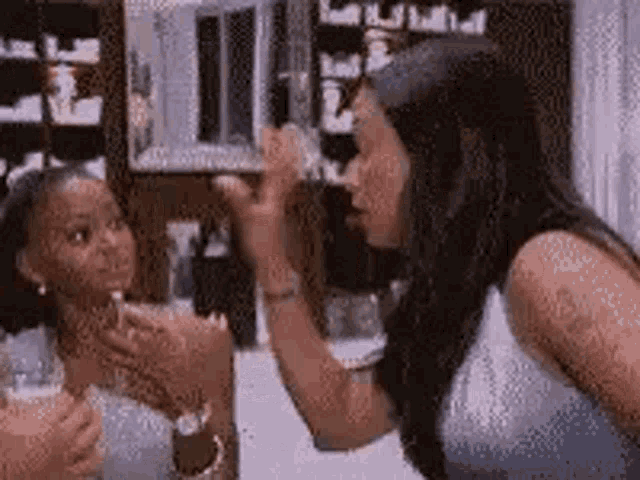 a woman is applying makeup to another woman 's face in a room .