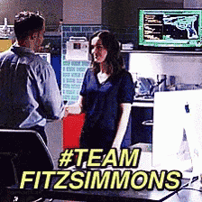 a man and a woman are standing in front of a computer with the words #team fitzsimmons written above them