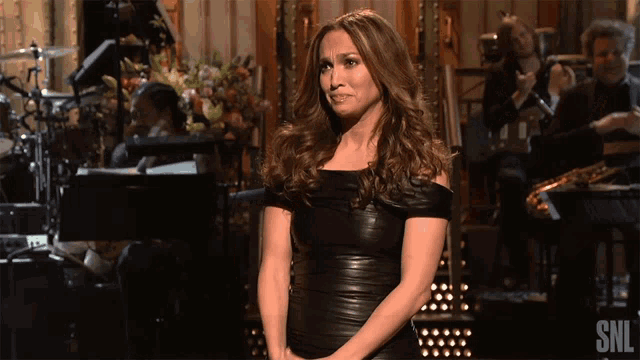 a woman in a black dress is standing in front of a snl sign
