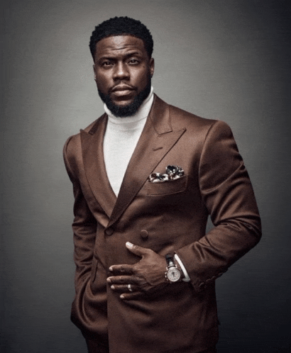 a man wearing a brown suit and a white turtleneck has a watch in his pocket