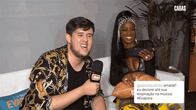 a man is talking into a microphone while a woman looks at her phone