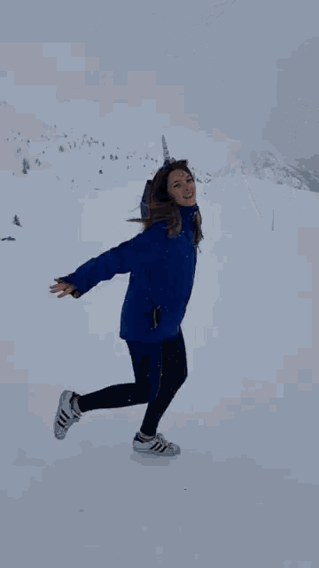 a woman wearing a blue jacket and a unicorn horn on her head is running in the snow