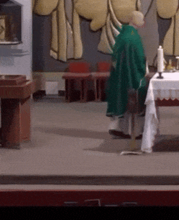 a man in a green robe stands in front of a table with a candle on it
