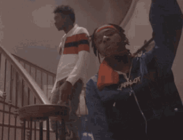 a man wearing a headband and a nike necklace stands on a set of stairs